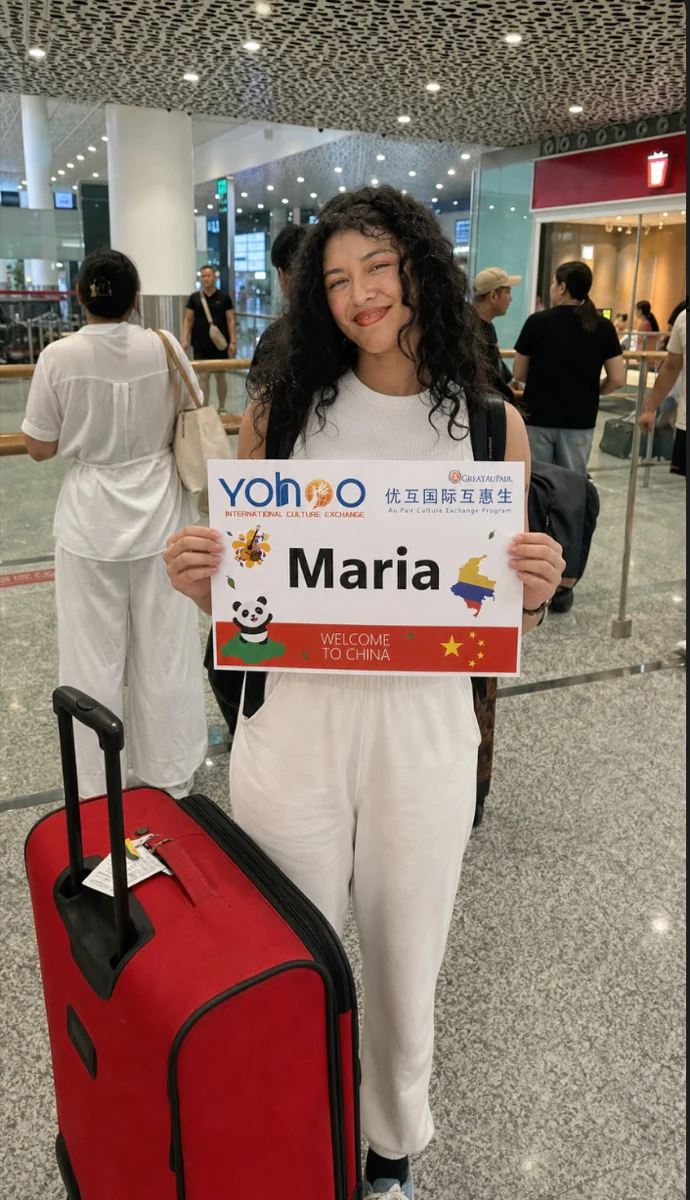 Maria arriving with luggage and a Yohoo welcome board